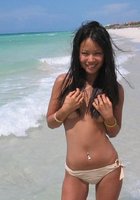 Смазливая азиатка стоит без лифчика на пляже 1 фотография