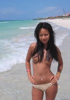 Смазливая азиатка стоит без лифчика на пляже 2 фотография