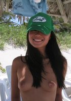 Смазливая азиатка стоит без лифчика на пляже 9 фотография
