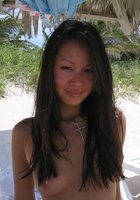 Смазливая азиатка стоит без лифчика на пляже 7 фото