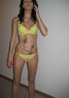 Брюнетка в желтом бикини стоит на фоне стены 4 фото
