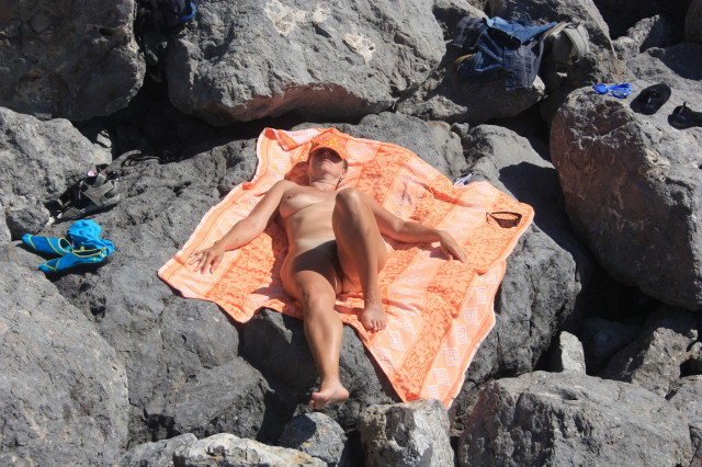 Голая зрелка лежит на камнях возле моря 6 фотография