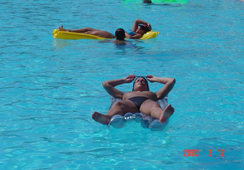 Взрослая брюнетка отдыхает в бассейне топлес 12 фотография