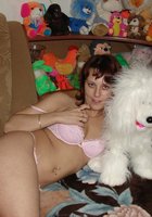 Развратная мамочка показывает сиськи на диване в куче мягких игрушек 4 фотография