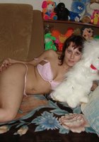 Развратная мамочка показывает сиськи на диване в куче мягких игрушек 3 фото