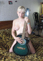Раздетая музыкантка позирует на кровати с гитарой в руках 4 фотография