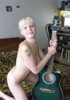 Раздетая музыкантка позирует на кровати с гитарой в руках 3 фотография