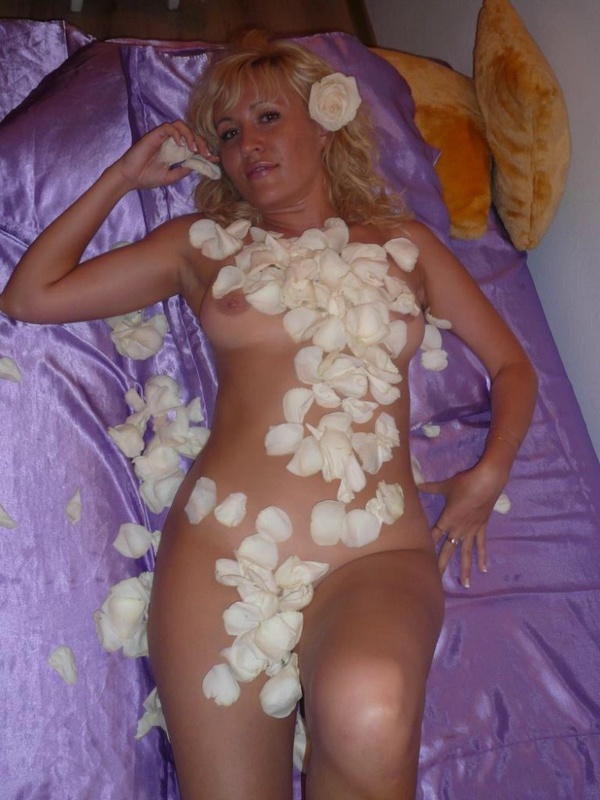 Блондинистая мамка обсыпала голое тело лепестками роз лежа на постели 15 фотография