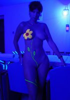 Голая девчонка с нарисованным цветком позирует в ультрафиолете 9 фото