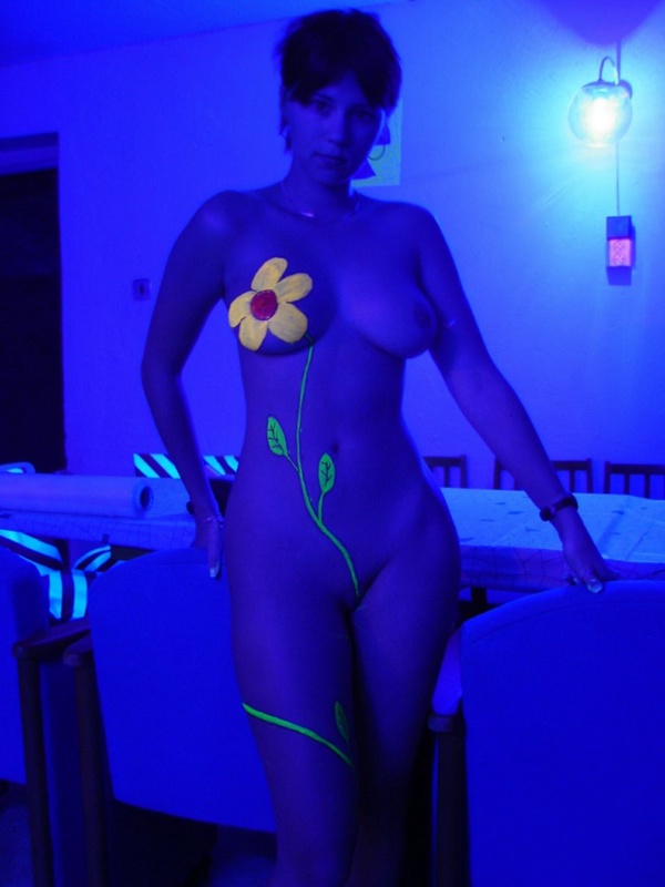 Голая девчонка с нарисованным цветком позирует в ультрафиолете 9 фотография