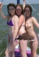 Три молодые подруги стоят на палубе яхты топлес 4 фото