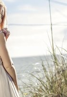 Красивая дева хвастается собой в траве на берегу моря 8 фото