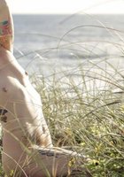 Красивая дева хвастается собой в траве на берегу моря 14 фотография