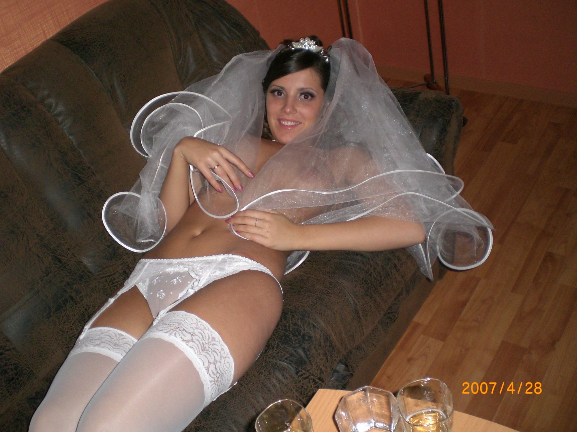 Развратная невеста в белых чулках позирует на кровати 6 фотография