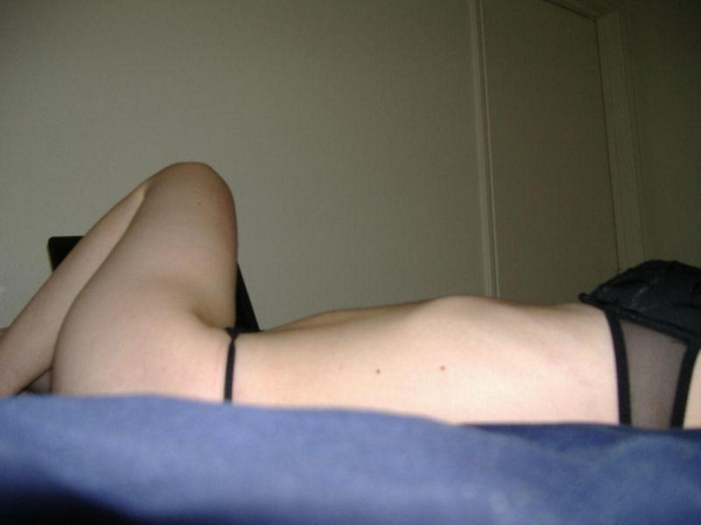 Зазноба с небритой киской лежит на постели в черных стрингах 7 фотография