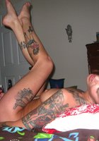 Брюнетка с татуировками по всему телу на постели мастурбирует красным вибратором 6 фото