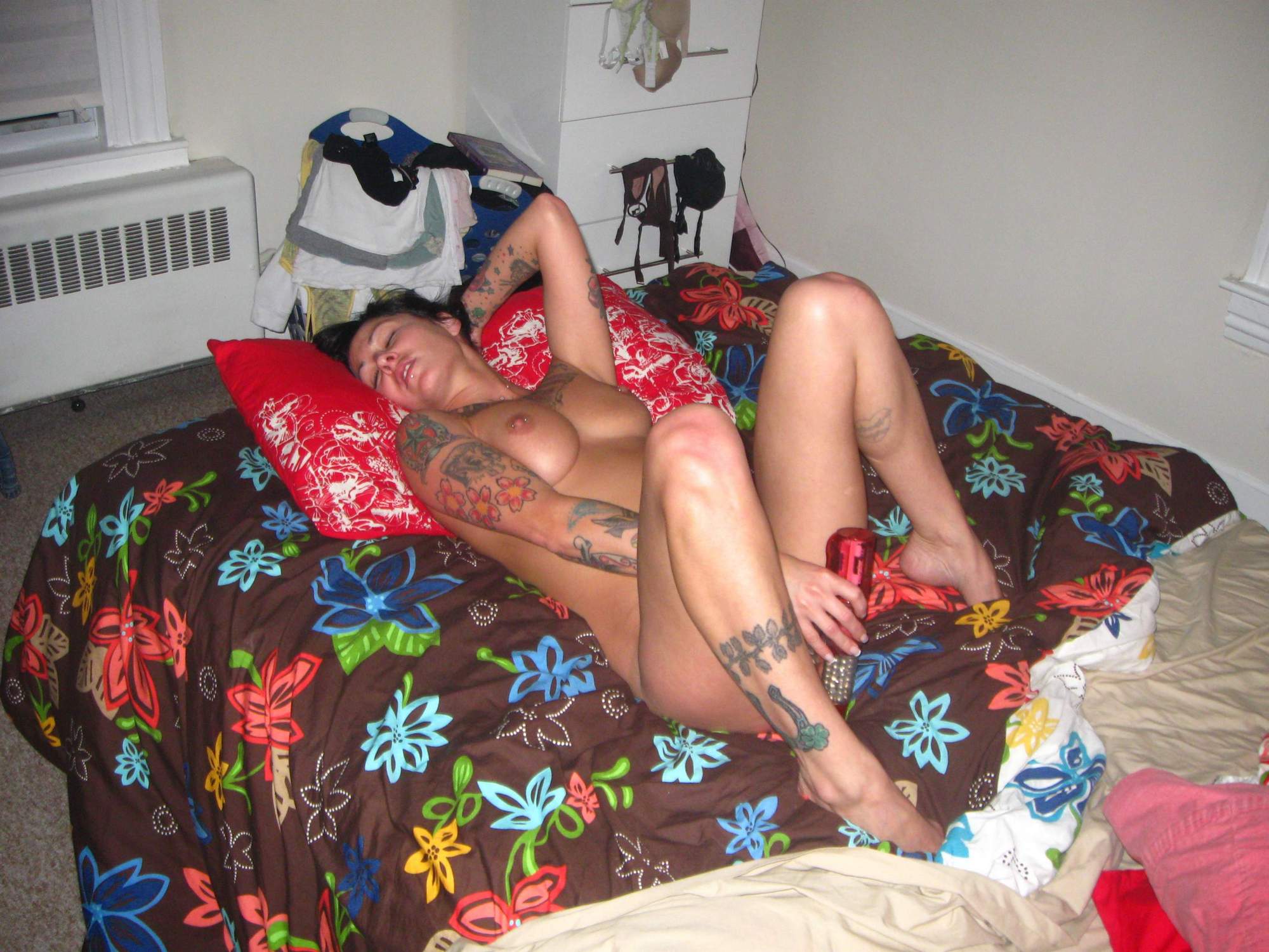 Брюнетка с татуировками по всему телу на постели мастурбирует красным вибратором 11 фотография