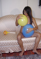 Стройная азиатка лежит на диване среди надувных шариков 11 фотография