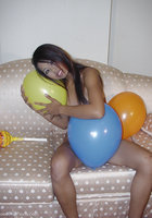 Стройная азиатка лежит на диване среди надувных шариков 12 фото