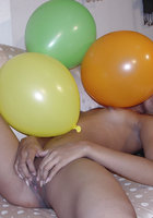 Стройная азиатка лежит на диване среди надувных шариков 15 фото