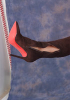 Блондинка в чулках примеряет сапоги с красной подошвой сидя на пуфе 14 фотография