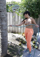 Баба с искусственной грудью поливает дерево стоя в оранжевых лосинах 1 фотография