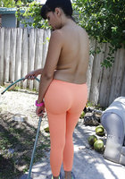 Баба с искусственной грудью поливает дерево стоя в оранжевых лосинах 3 фотография