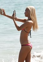 Худая блонда в розовом бикини зашла в море, не выпуская из рук телефон 2 фотография