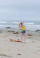 Рыжая серфингистка позирует в купальнике на берегу океана 1 фото