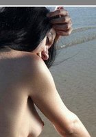 Длинноволосая брюнетка позирует голышом на морском берегу 5 фото