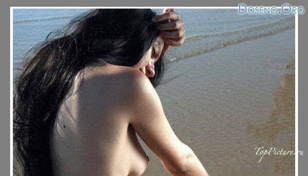 Длинноволосая брюнетка позирует голышом на морском берегу 5 фотография