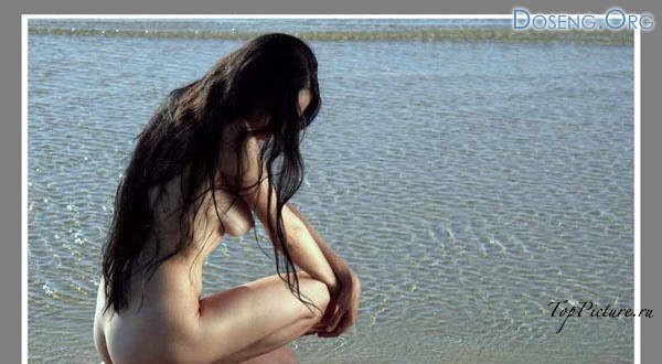 Длинноволосая брюнетка позирует голышом на морском берегу 6 фотография