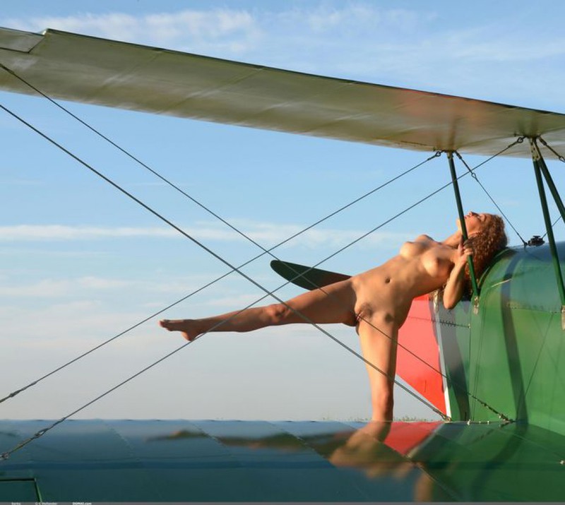 Кучерявая стройняшка позирует без одежды и белья на крыле самолета 4 фотография